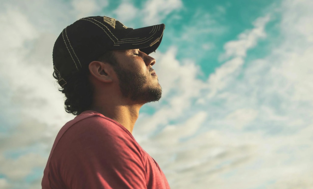 man staat in zon en neemt diep adem