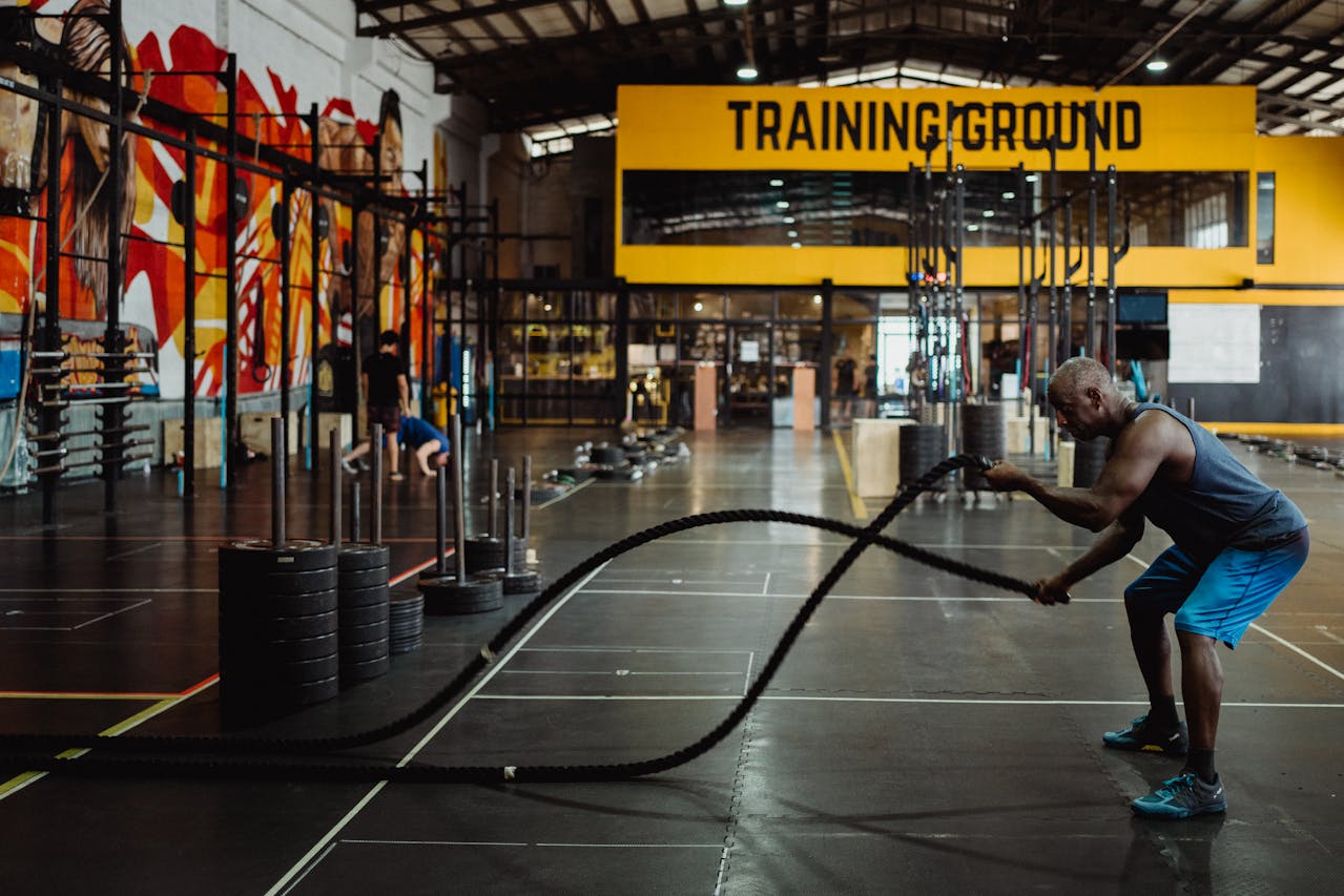 Man traint met battle ropes in een gym, gericht op spiermassa opbouwen en conditieverbetering.