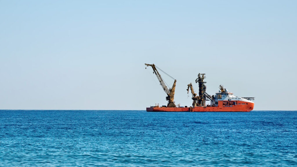 Offshore schip met moderne scheepskranen aan dek op open zee

