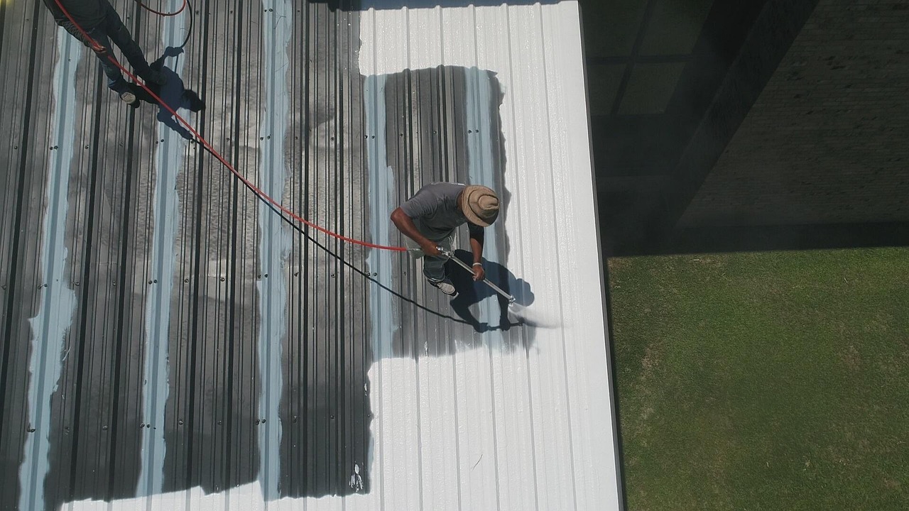 Man brengt uv-coating aan op een metalen dak om bescherming tegen zonlicht en weersinvloeden te verlengen.