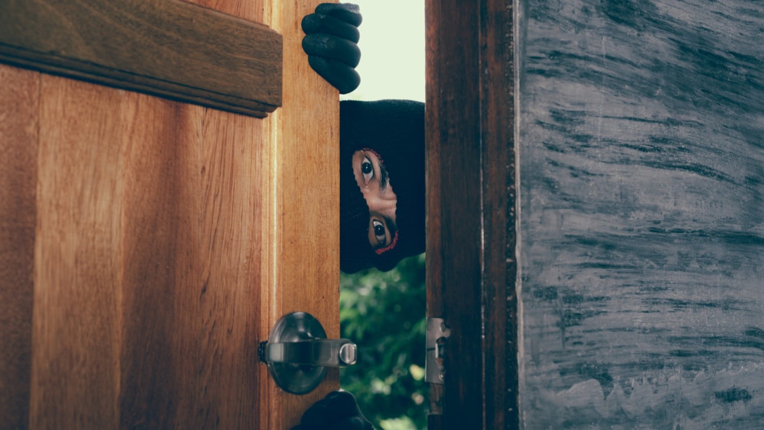 Persoon kijkt door geopende deur na inbraak als aanleiding voor noodbeveiliging na inbraak