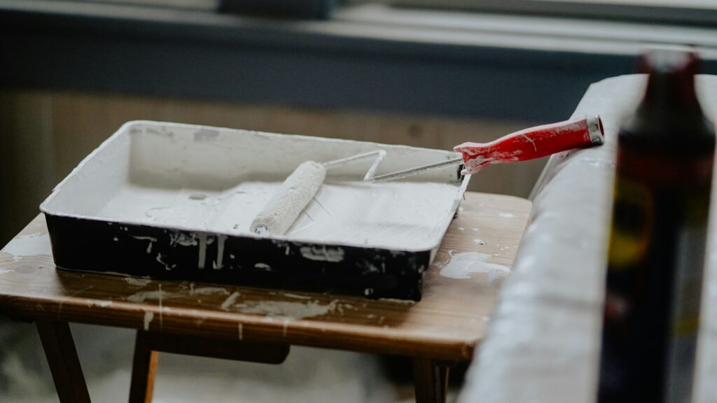 Verfbak met roller klaar voor tweede verflaag aanbrengen op een houten oppervlak