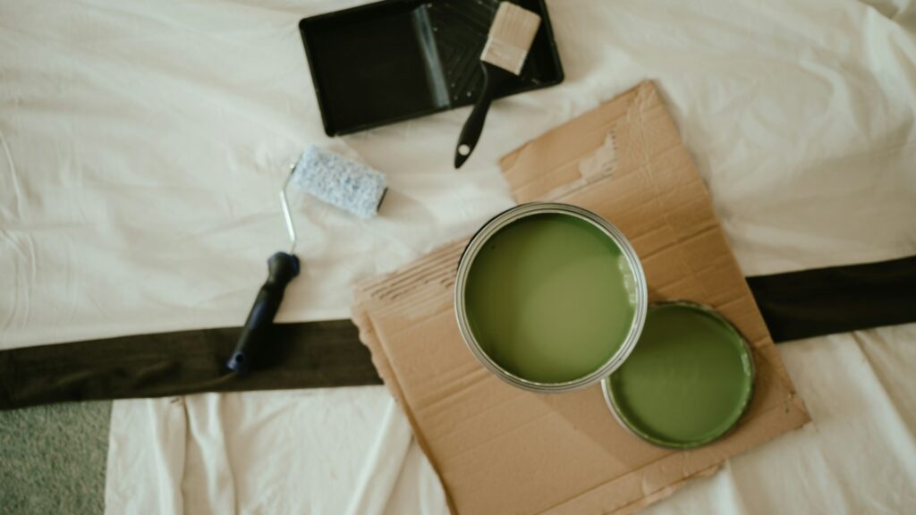 Schilderwerk aan buitengevel met ladders tijdens tweede verflaag aanbrengen op een woning